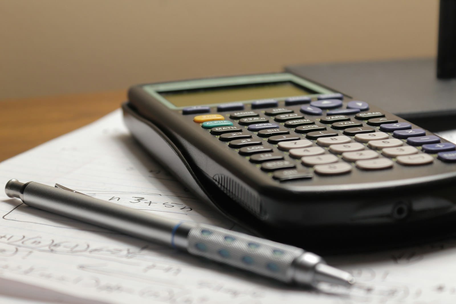 Calculator and pen on a page of handwritten calculations